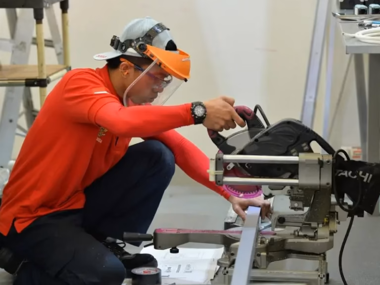 Man with protective face shield on using power tools while working a skill trade job.